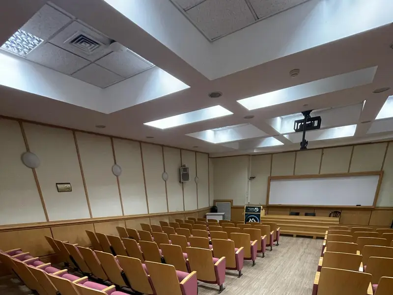 אודיטוריום במכללה עם שורות כיסאות מדורגות וריצוף PVC דמוי עץ במעברים