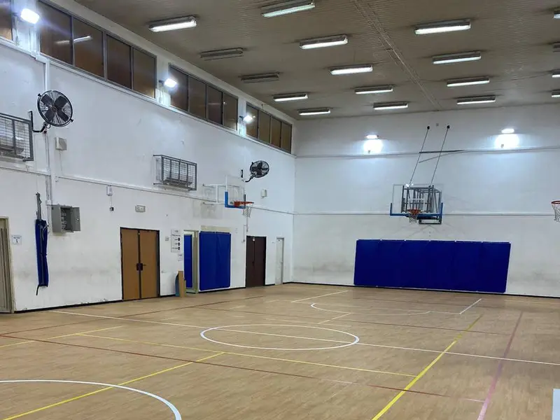 אולם ספורט עם רצפת PVC דמוית עץ, סלי כדורסל ומגני קיר כחולים